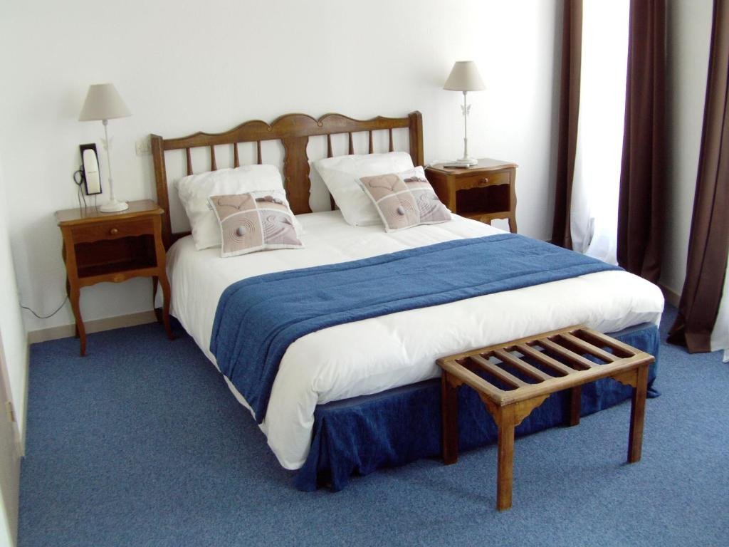 Chambre double du Grand Hotel avec tête de lit en bois et couvre-lit bleu
